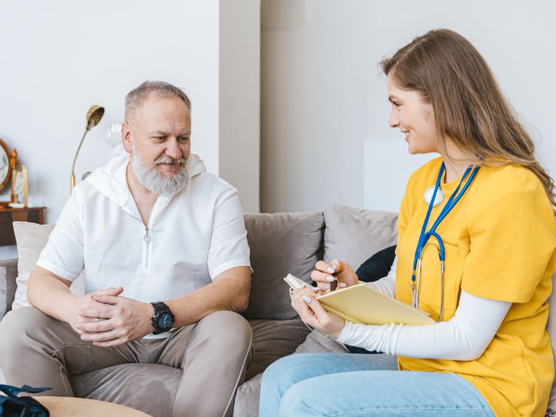 Nurse consulting with an elderly patient at home